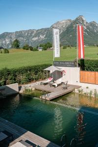 a pool of water with a table and chairs and mountains at DAS SALZBERG Hideaway Bad Aussee - Adults only in Bad Aussee