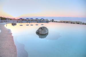 a pool with a rock in the water next to the beach at 19 Summer Suites in Santa Cesarea Terme