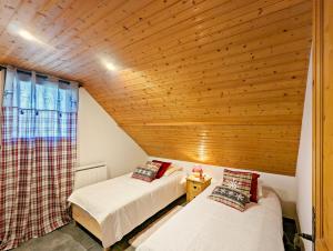 two beds in a room with a wooden ceiling at Chalet Stella 5* à 2mn des pistes in Saint-Chaffrey