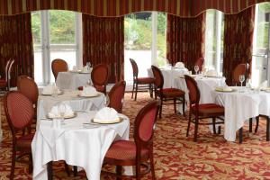 a dining room with white tables and chairs at Buckatree Hall Hotel in Telford