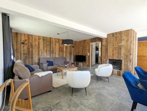 een woonkamer met een bank en stoelen en een tv bij Chalet Stella 5* à 2mn des pistes in Saint-Chaffrey