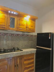 Una cocina con gabinetes de madera y un refrigerador negro. en Sedap malam house, en Lovina 7 fotos más