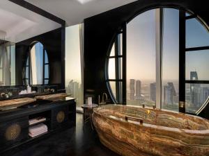 a bathroom with a large wooden tub and a large window at Fairmont Doha in Doha