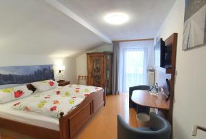 a bedroom with a bed and a desk and a television at Hotel Garni Haus Alpine - Chiemgau Karte inkl in Ruhpolding