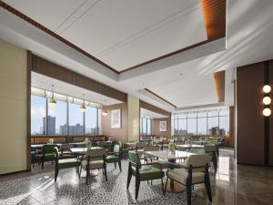 une salle à manger avec tables, chaises et fenêtres dans l'établissement Hilton Garden Inn Ganzhou Longnan, à Longnan