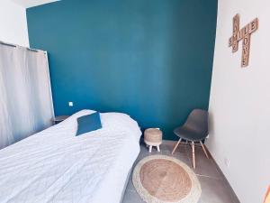 1 dormitorio con cama, silla y pared azul en Grand studio pour 2 Perpignan Bir Hakeim, en Perpiñán