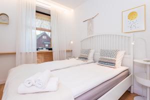 a white bedroom with two beds and a window at Smeltė - Family Suite Apartment in Juodkrantė in Juodkrantė