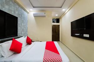 Hotel Sunrise في Naroda: غرفة نوم بسرير ومخدات حمراء وتلفزيون
