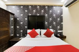 a bedroom with a large bed with red pillows at Hotel Sunrise in Naroda