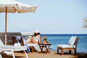 a woman sitting on a table on the beach at Hersonissos Beach Villa in Hersonissos