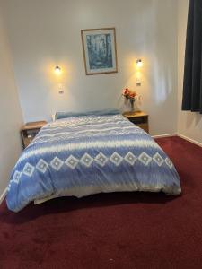 a bedroom with a bed with a blue comforter at Oasis Motel - waiouru in Waiouru