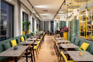 a row of tables in a restaurant with yellow chairs at Vienna House Easy by Wyndham Berlin Potsdamer Platz in Berlin