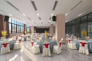 - une salle de banquet avec des tables blanches, des chaises et des bows dans l'établissement Days Inn by Wyndham Chongqing Tongliang, à Tongliang
