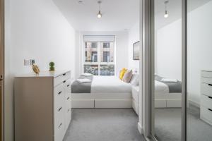 een witte slaapkamer met een bed en een spiegel bij Madika Homes - Cosy 2 Bed 2 Bath in Colindale London in Colindale