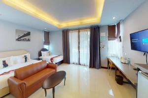 een hotelkamer met een bank, een bed en een tv bij Nutchana Hill Boutique Hotel in Hat Yai