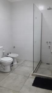 a bathroom with a toilet and a glass shower at Complejo Ermindo I in Rafaela