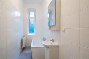 ein weißes Badezimmer mit einem Waschbecken und einem Spiegel in der Unterkunft Apt Volt - Modern, neu, komplett ausgestattet, 4 Einzelbetten, zentral mit Waschmaschine Spülmaschine TV Herd Backofen Mikrowelle in Fürstenwalde