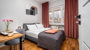 a bedroom with a bed and a desk with a desk at Apartamenty Złota by Sun & Snow in Warsaw
