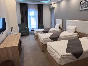 a hotel room with three beds and a television at Jupiter -ZamZam-Madinah Halal Hotels Group in Baku