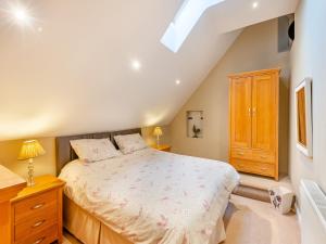 a bedroom with a bed and a wooden cabinet at Oak Cottage in Ware
