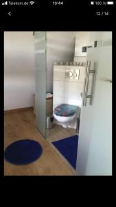 a bathroom with a toilet and a blue rug at Aussichtszimmer mit modernem Glasbad und Balkon in Koblenz