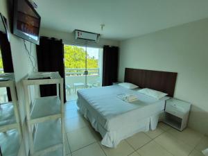 Habitación de hotel con cama y TV en Divinos Flat Carneiros en Praia dos Carneiros