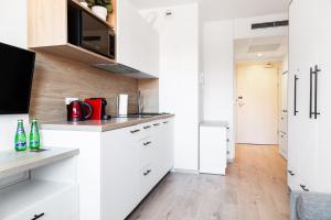 a white kitchen with white cabinets and a wooden floor at Lumen Studio in Wrocław