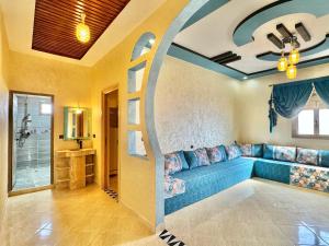 a living room with a blue couch and an archway at Merzouga DesertView Apartment in Merzouga
