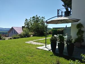 a patio with an umbrella and two chairs and a table at Ferienwohnungen Alpenblick mit Garten und Terrasse in Kirchdorf im Wald