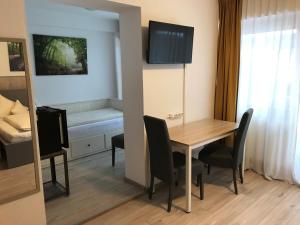 a room with a table and chairs and a bed at Abendruhe Hotel - kontaktloser Check In in Oberhaching