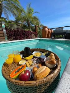una cesta de pan y fruta en una mesa junto a una piscina en Casa com Piscina, Rede Suspensa e Praia Privativa, en Mangaratiba
