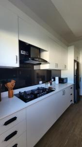 a kitchen with white cabinets and a stove top oven at Modern Boho Apt in Punta Cana in Punta Cana