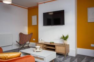 a living room with a couch and a tv on a wall at Vacant Nests North Parade in Whitley Bay