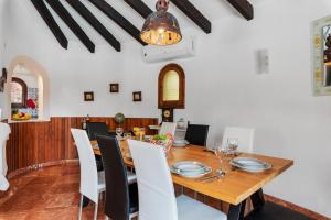 une salle à manger avec une table en bois et des chaises blanches dans l'établissement Villa Axel - PlusHolidays, à Calp