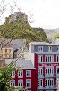 un bâtiment rouge avec un panneau d'hôtel en face d'une montagne dans l'établissement Hôtel Saint Etienne, à Lourdes