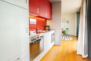 una cucina con armadi rossi e lavandino di Senevita Residenz & Apartments Muri bei Bern a Berna