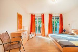 Schlafzimmer mit orangefarbenen Vorhängen, einem Bett und einem Stuhl in der Unterkunft Strandhaus Fiete - Haus Poelblick - ABC247 in Hohen Wieschendorf