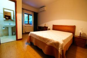 een slaapkamer met een bed en een badkamer met een wastafel bij Casa do Lago - Geres in Geres