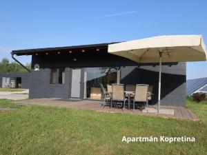 um pátio com cadeiras e um guarda-sol em frente a uma casa em Apartmány Štramberk em Štramberk