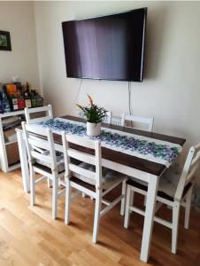 uma mesa de jantar com cadeiras brancas e uma televisão em Cosy private room em Streatham Hill