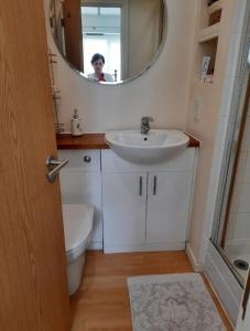 a woman in a bathroom with a sink and a mirror at Cosy private room in Streatham Hill