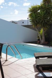 una piscina con una silla y palmeras en VILLA BERMEJA 1 by Villitas, en Playa Blanca