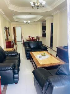 a living room with leather couches and a wooden table at EliteOysterbay - 2 Bedroom Apartment in Dar es Salaam
