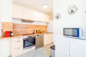 a kitchen with white cabinets and a tv on the wall at Idéal Pro et Famille en Hypercentre - 3 lits in Corbeil-Essonnes