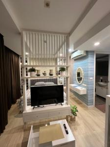 a living room with a television on a bed at I chill Six Room in Ban Bang Saen (1)