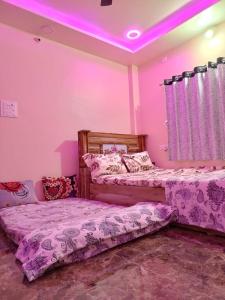 two beds in a room with purple lighting at SHRISHAILAM FARM AND YATRI NIWAS in Akalkot