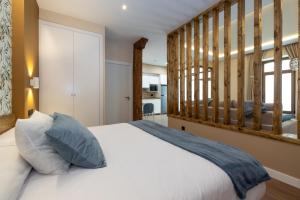 una camera da letto con un letto bianco con testiera in legno di Apartamentos LA CAÑADA DE OSMA a El Burgo de Osma