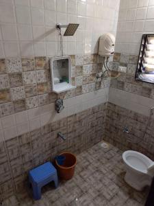 a tiled bathroom with a toilet and a window at SHRISHAILAM FARM AND YATRI NIWAS in Akalkot