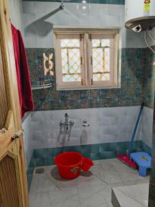 a bathroom with a red bucket in the shower at MAGRAY GUEST HOUSE in Tangmarg