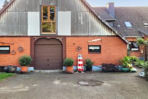 une maison en brique orange avec un garage et quelques plantes dans l'établissement Mole Valley Ranch Fewo1, à Elmlohe